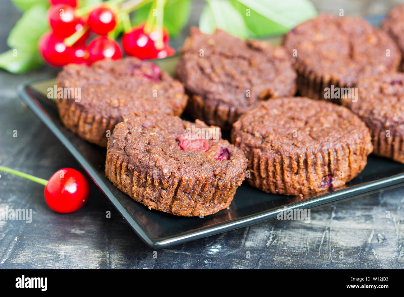 Chocolate muffin with fresh cherries on a plate Stock Photo