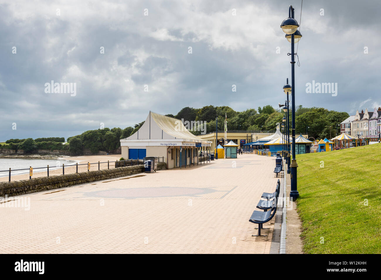The promenade at Barry Island is bright but quiet during a sunny spell on a cloudy and showery early summer day. Stock Photo