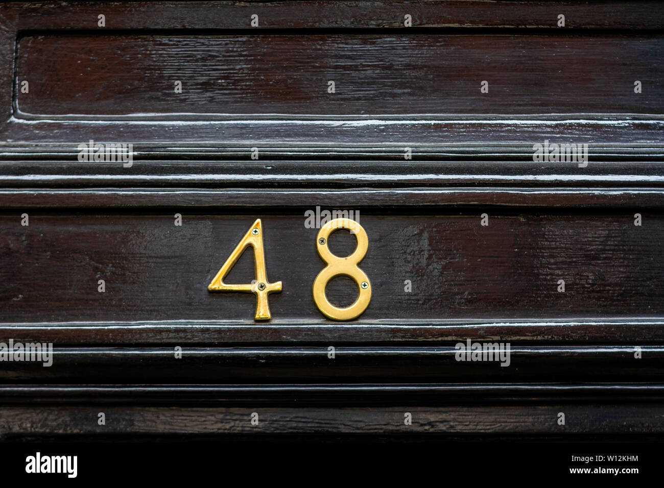 House number 48 with the forty-eight in metal digits on a black painted old wooden front door Stock Photo