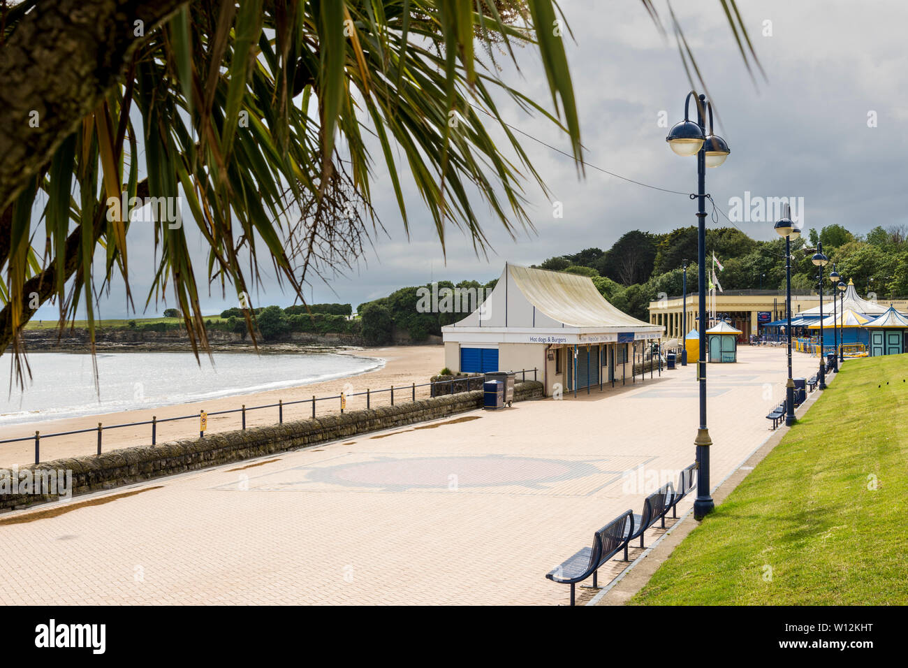 The promenade at Barry Island is bright but quiet during a sunny spell on a cloudy and showery early summer day. Stock Photo