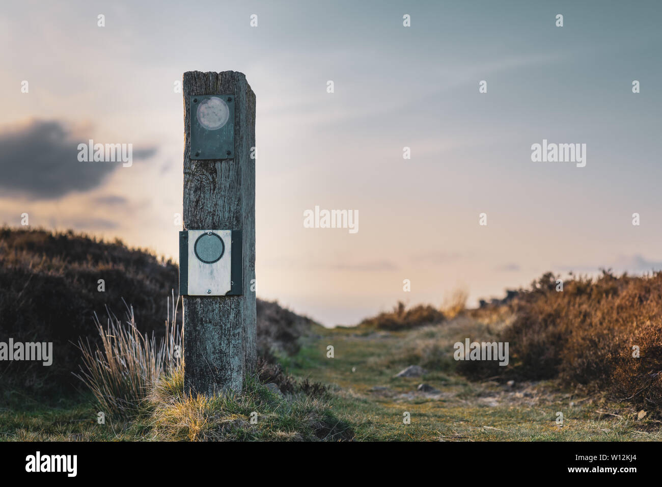A blank signpost in a national park in the UK with a calm sunset behind it Stock Photo