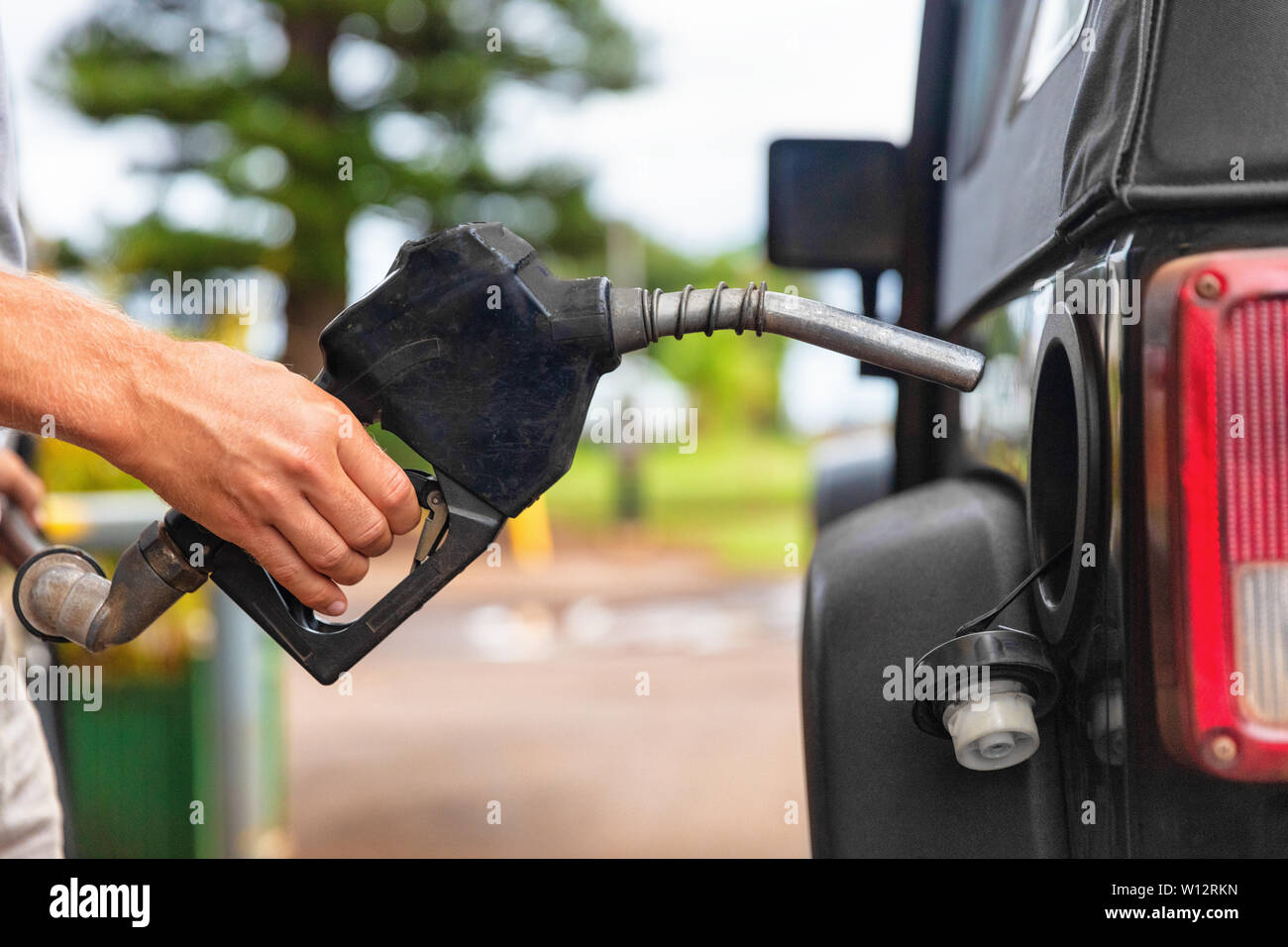 Gas station pump. Man filling gasoline fuel in car holding nozzle. Close up. Stock Photo