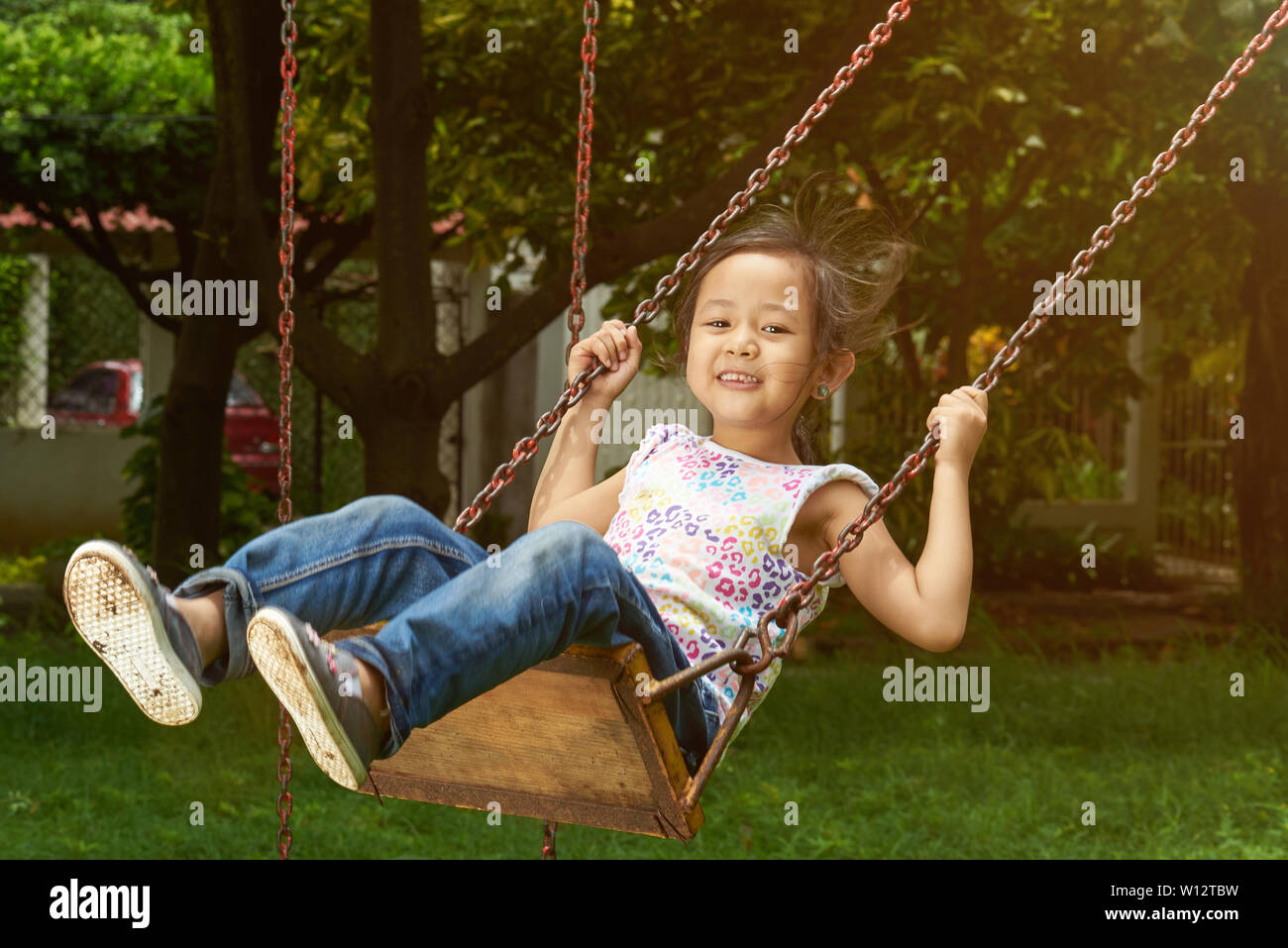 Asian girl smiling on a swing. Filipina kid. Stock Photo