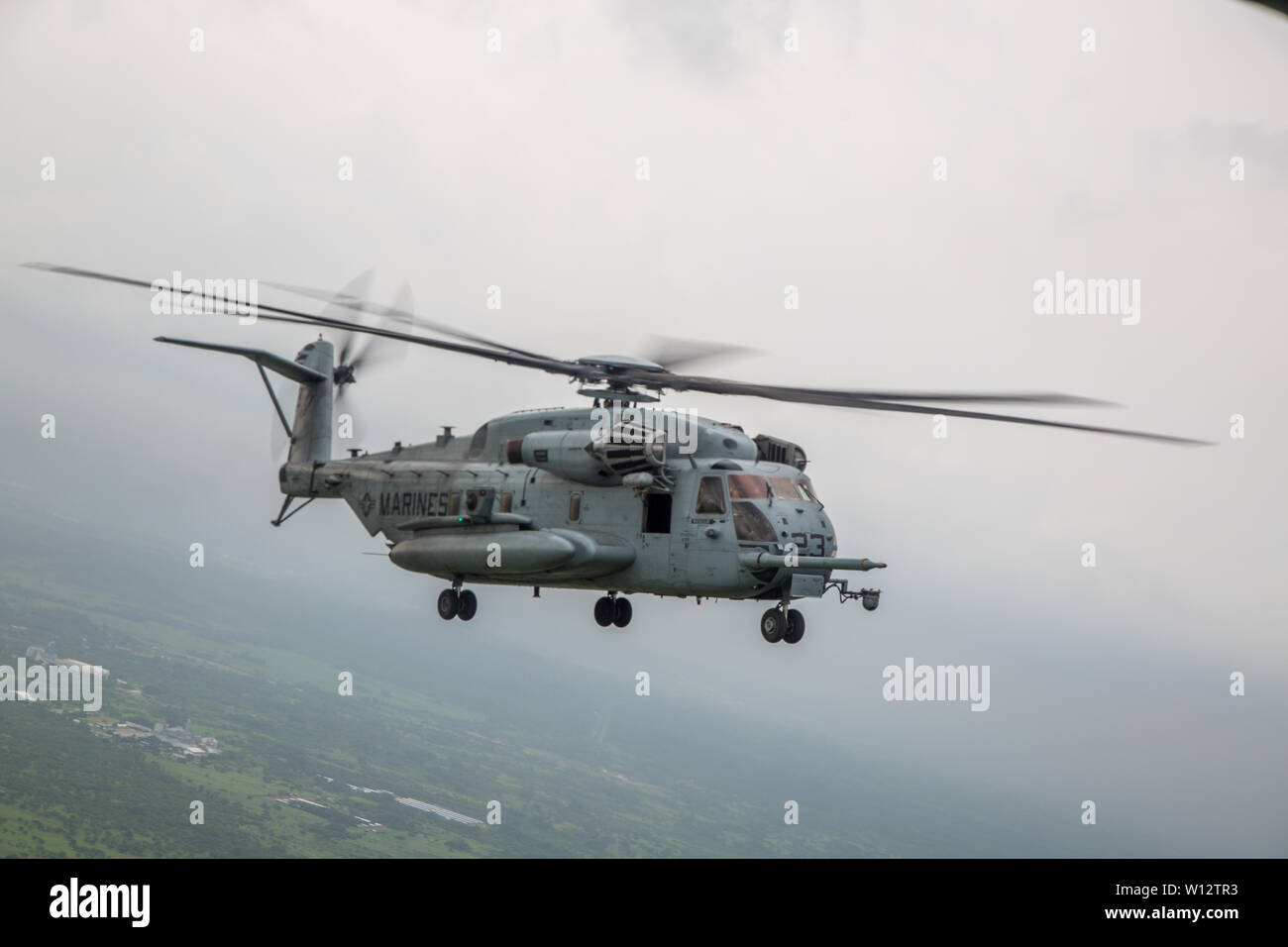 A CH-53E Super Stallion with Special Purpose Marine Air-Ground Task Force – Southern Command flies over Puerto San Jose, Guatemala, June 25, 2019. The task force is conducting training and engineering projects hand-in-hand with partner nation military members in the region during their deployment that coincides with hurricane season. (U.S. Marine Corps photo by Cpl. Stanley Moy) Stock Photo