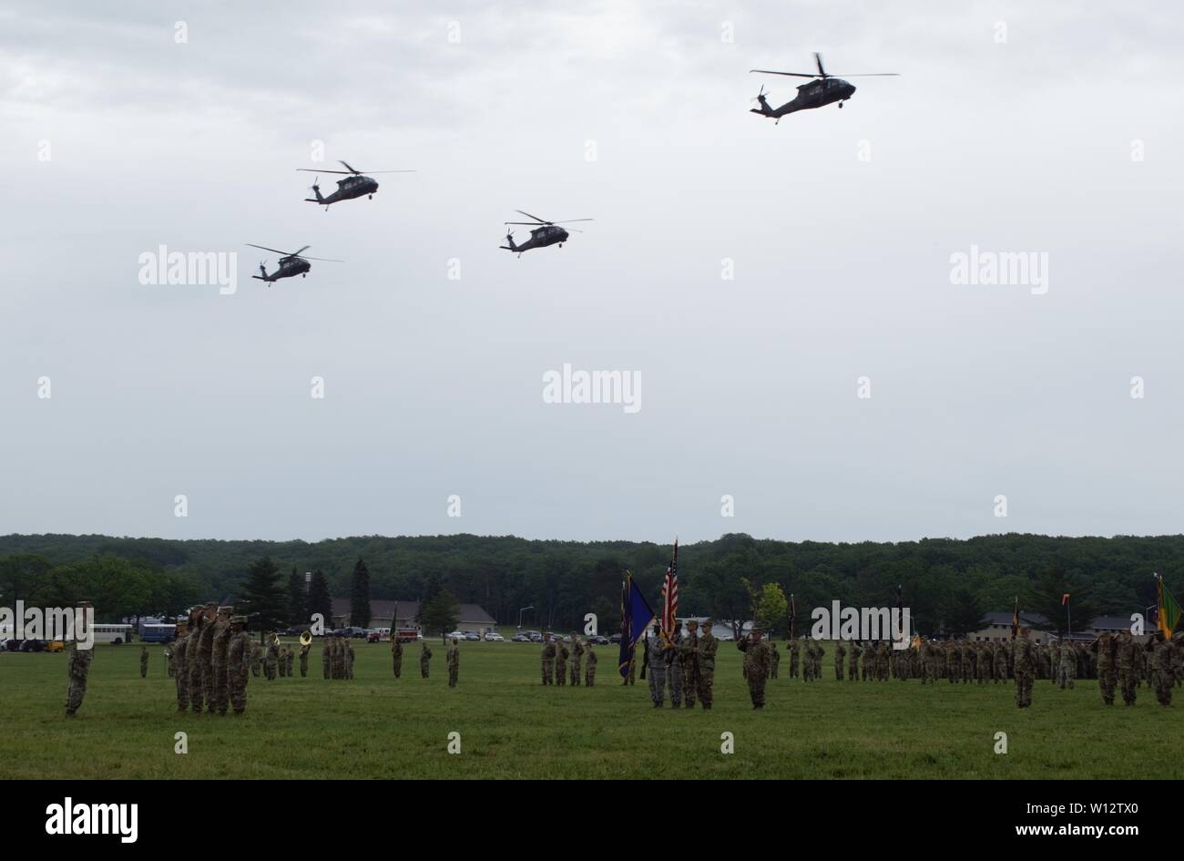 Black Hawk helicopters from the Michigan National Guard perform a flyby during the National Anthem ceremony at the 2019 Michigan National Guard Memorial and Pass in Review, Camp Grayling Maneuver Training Center, Grayling, Mich., June 28, 2019 (Michigan National Guard photo by 1st Lt. Andrew Layton/released). Stock Photo