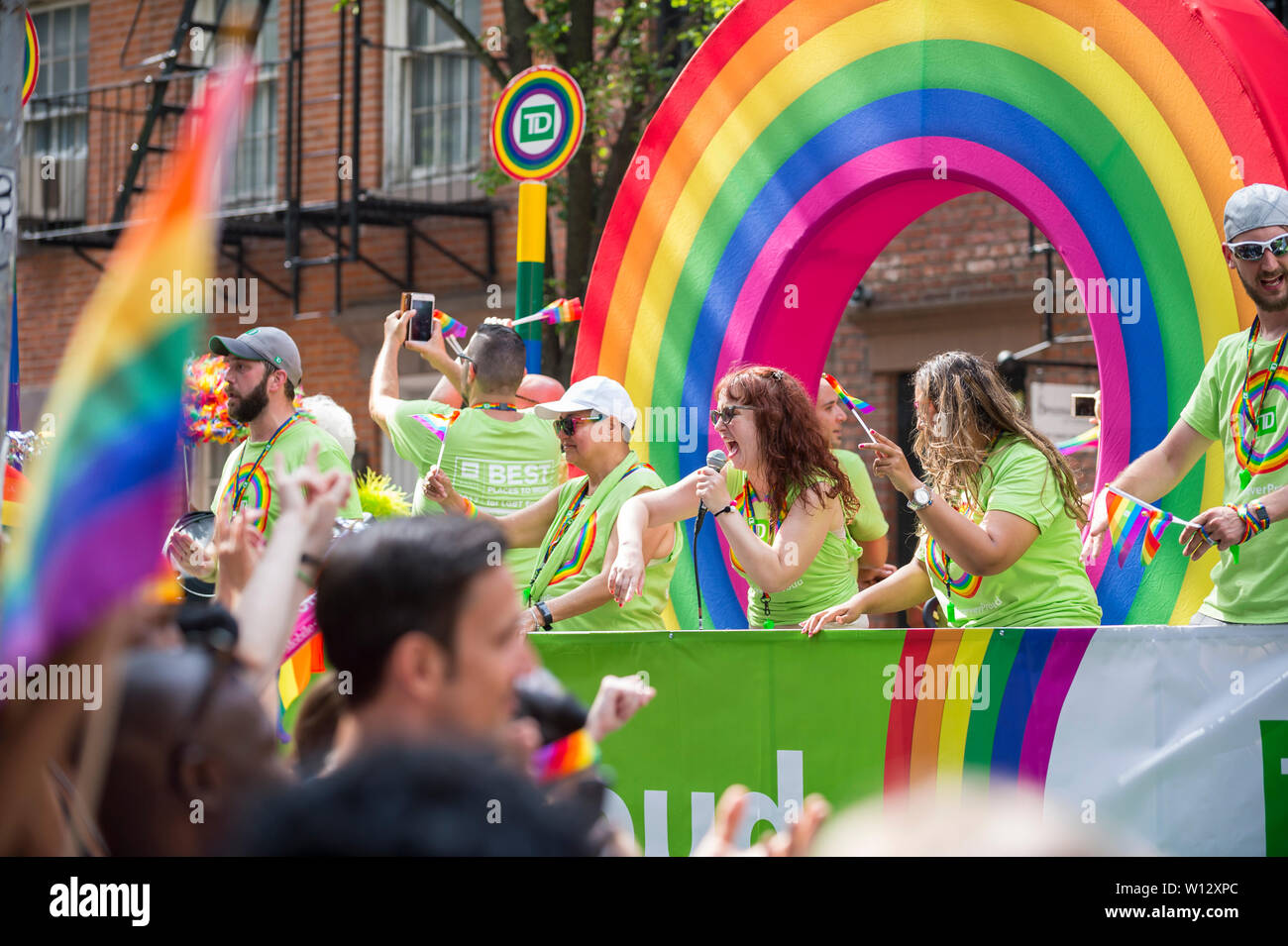 NEW YORK CITY - JUNE 25, 2017: Participants wave flags on a float with a rainbow arch sponsored by TD Bank in the annual Pride Parade in the Village. Stock Photo