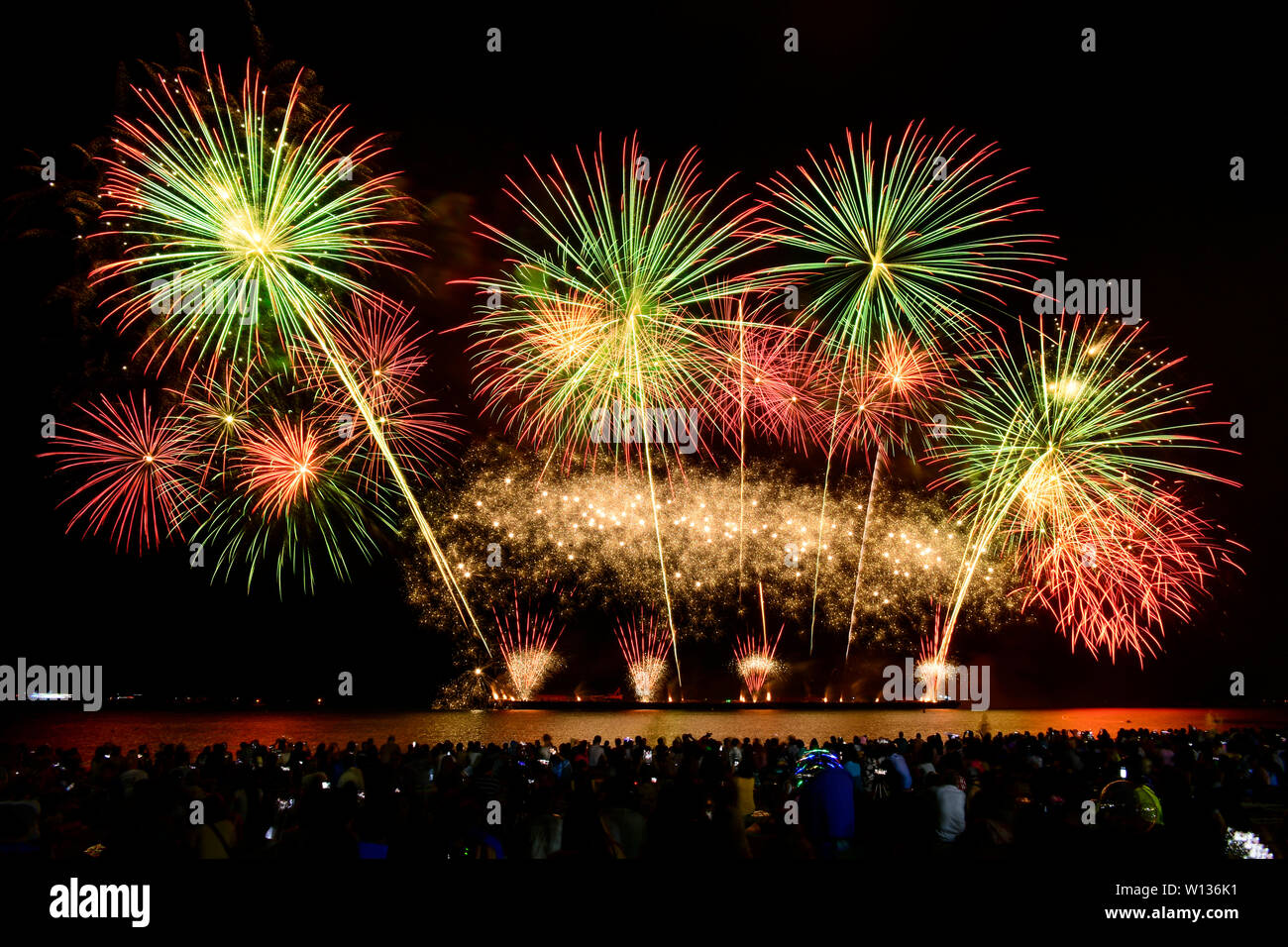 Colorful fireworks celebration and the night sky background with crowded people on the beach. Stock Photo