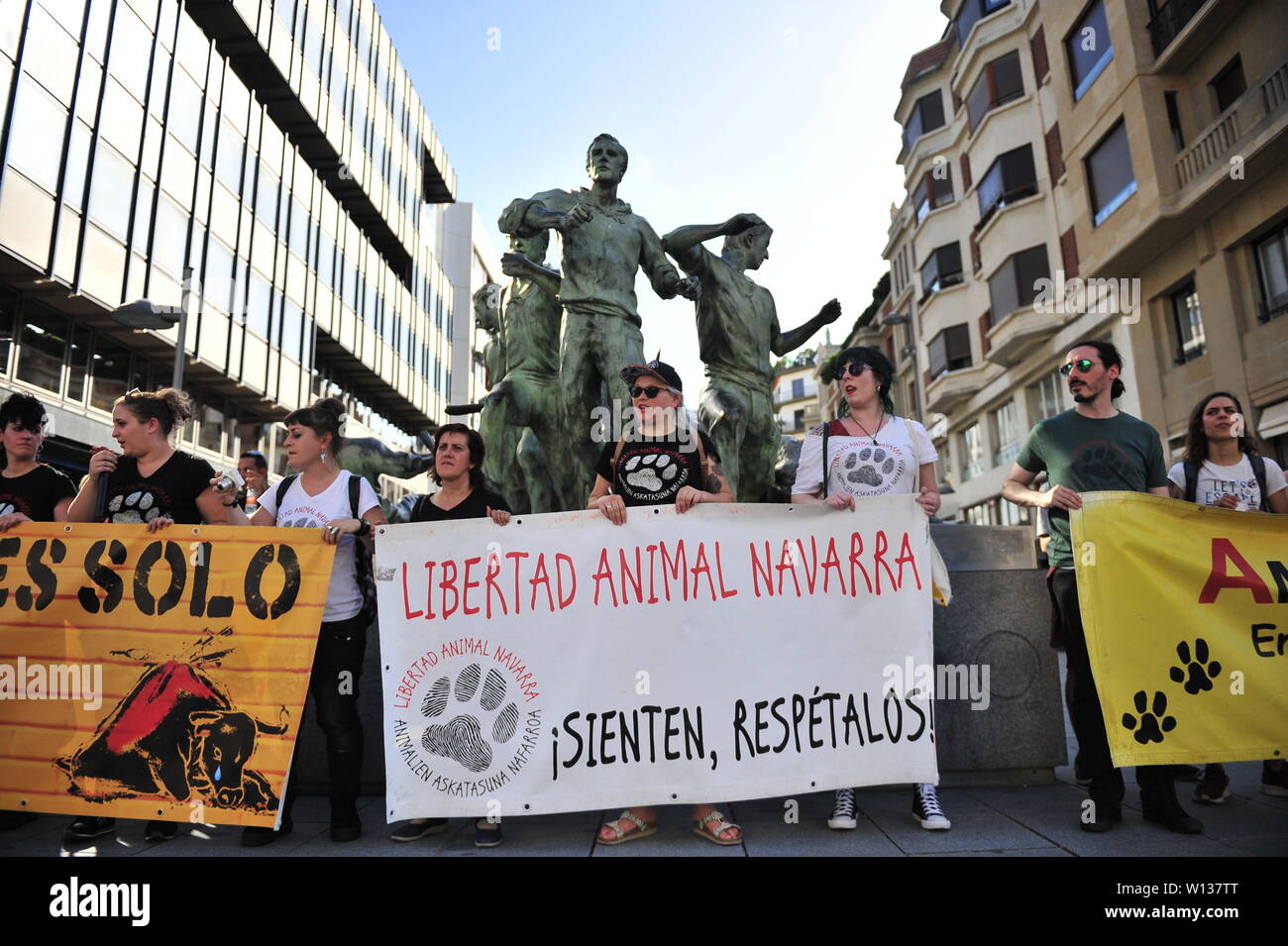 Pamplona, Spain. 29th June, 2019. Demonstrators with banners seen in front of the monument to the running of the bulls in Pamplona during a demonstration to demand the abolition of bullfighting.Under a temperature of over 40 degrees Celsius, a demonstration called by anti-bullfighting groups has been held today in Pamplona, the capital of Navarre. On the occasion of the festivities of San Fermin, to show his rejection for 'the murder' of 60 bulls in the Plaza de Toros Monumental of the city, during the celebration of the bullfights. Credit: SOPA Images Limited/Alamy Live News Stock Photo