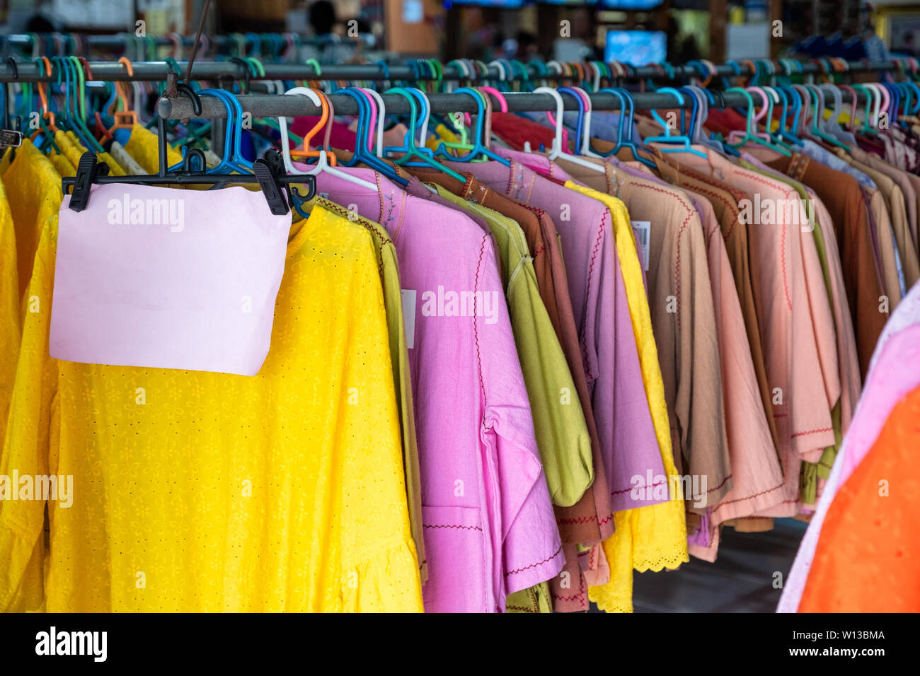 Colorful clothes made of cotton fabric hanging on rail in store Stock