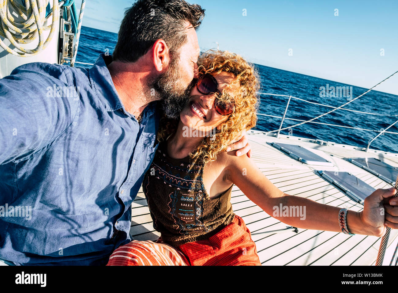 Happy tourist couple of traveler people in love enjoying the sail boat trip together having fun and smiling - cheerful adult man and woman under the s Stock Photo