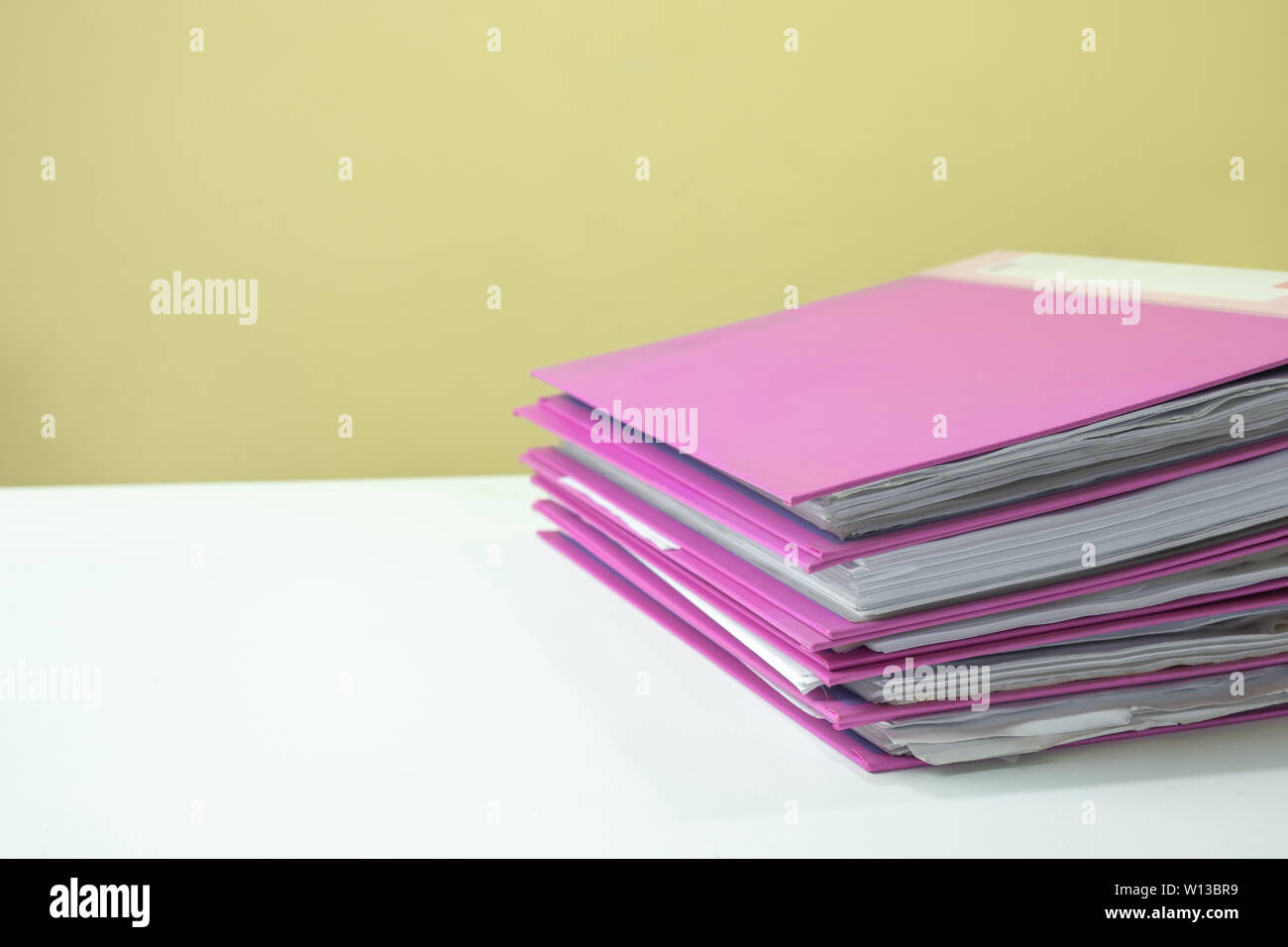 Stack of account file documents on white desk with yellow background ...
