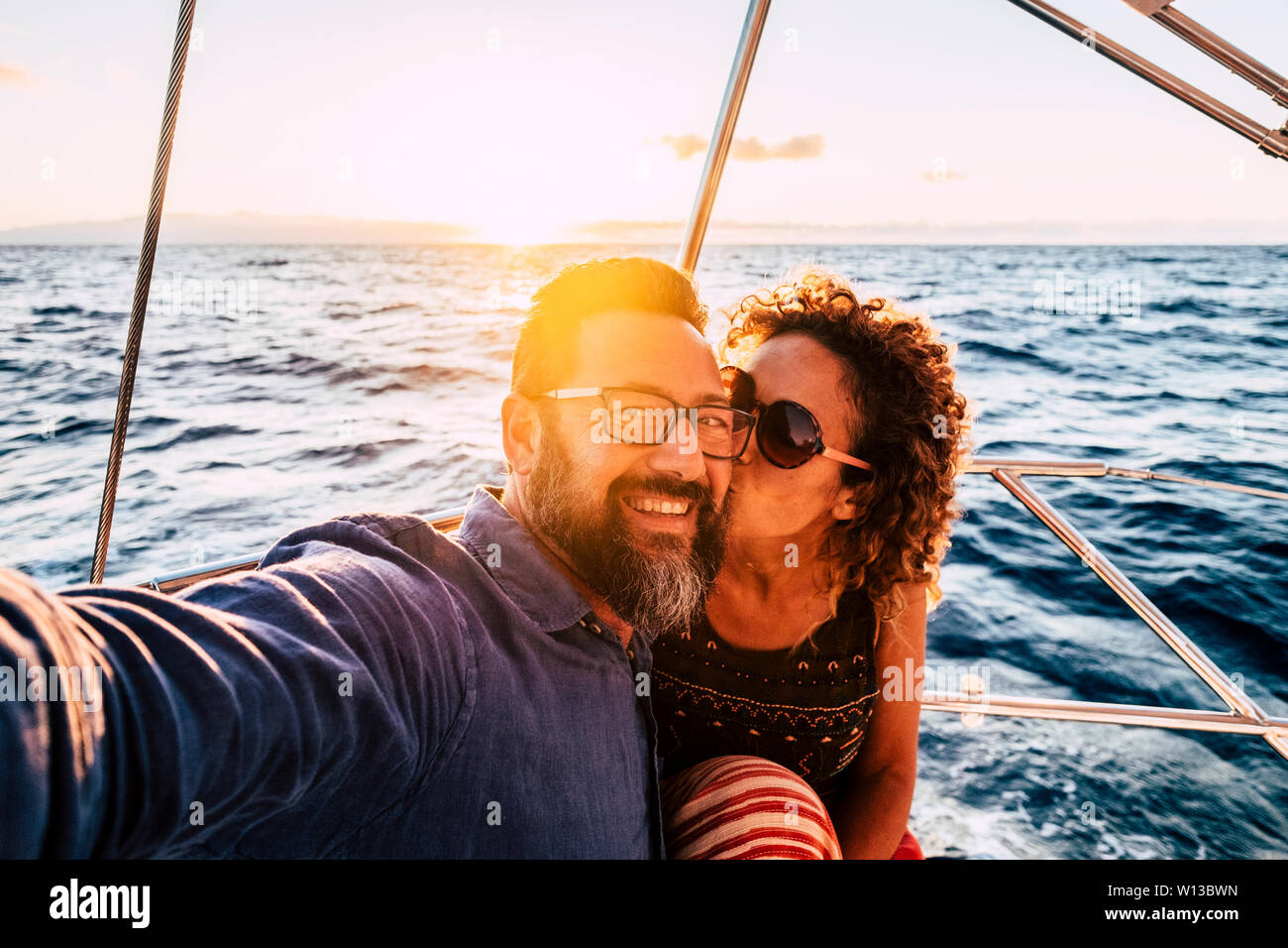 Romantic and happy people caucasian couple kissing and taking selfie on a sail boat - luxury and joyful lifestyle for cheerful adults man and woman to Stock Photo