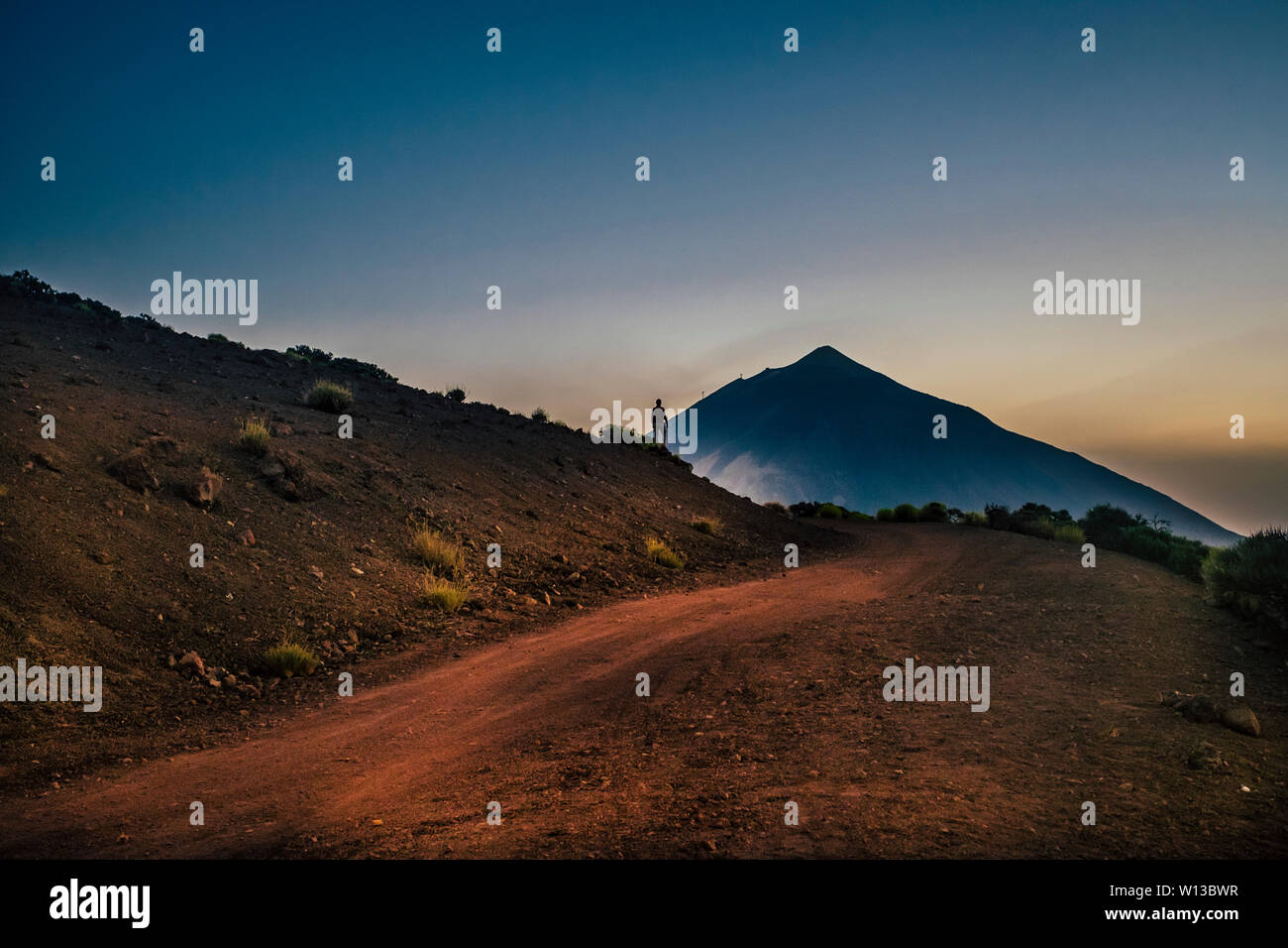 Scenic landscape with standing man in front of the mountain - travel and adventure expedition concept - people exploring the beauty and the wild Stock Photo