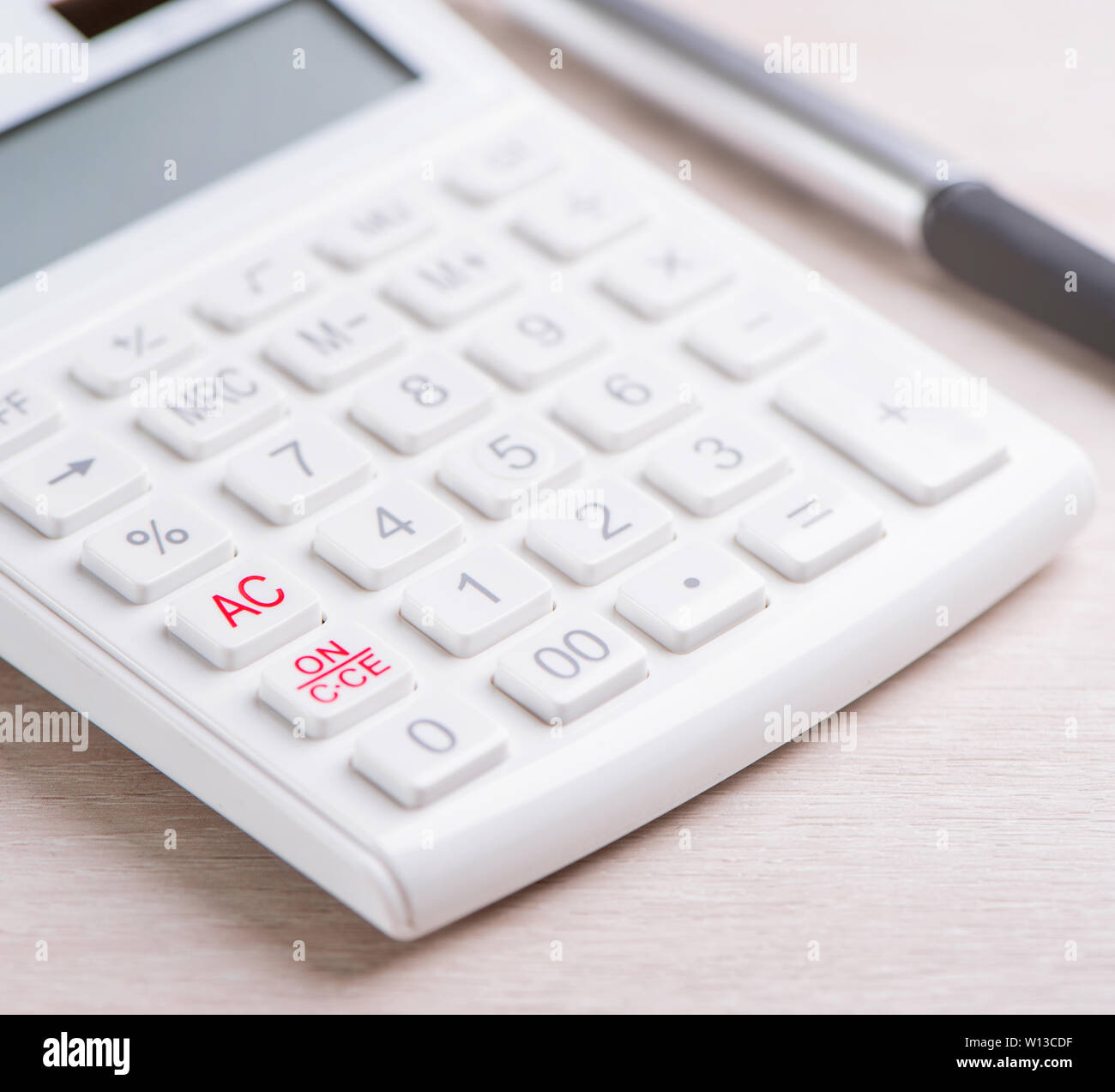 White calculator and pen on bright wooden table, analytics and statistics of financial profit, investment risk concept, copy space, macro, close up Stock Photo