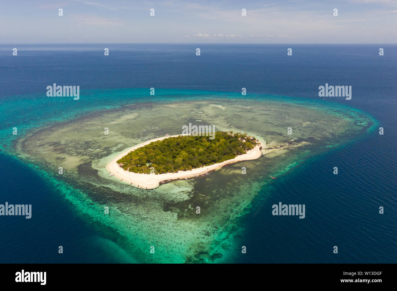 Mantigue Island, Philippines. Atoll with a tropical island. Round islet with a white beach and tropical trees, view from above. Stock Photo