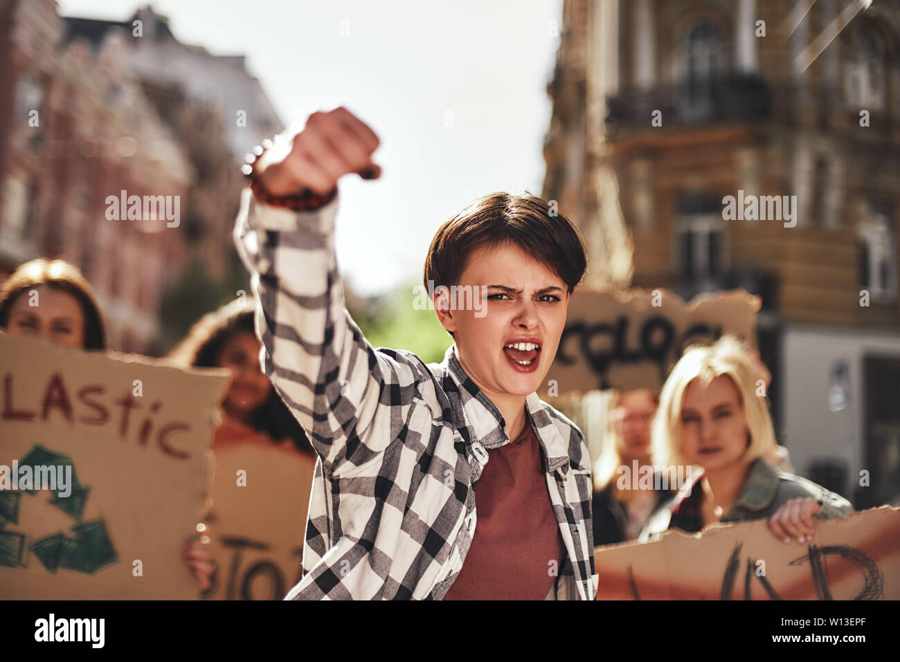 Emotional young woman screaming a slogan and leading a group of demonstrators on the road. Demonstration. Protest concept. Women rights Stock Photo
