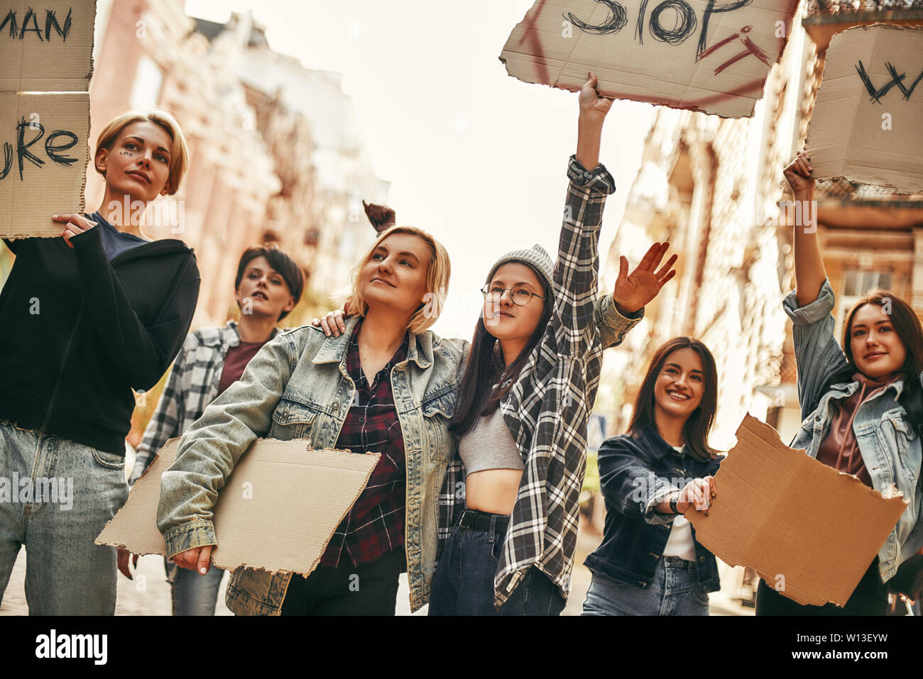 Stop violence against women. Group of young female activists are holding signboards with different slogans while standing on the road during a women's march. Human rights. Protest concept. Women rights Stock Photo