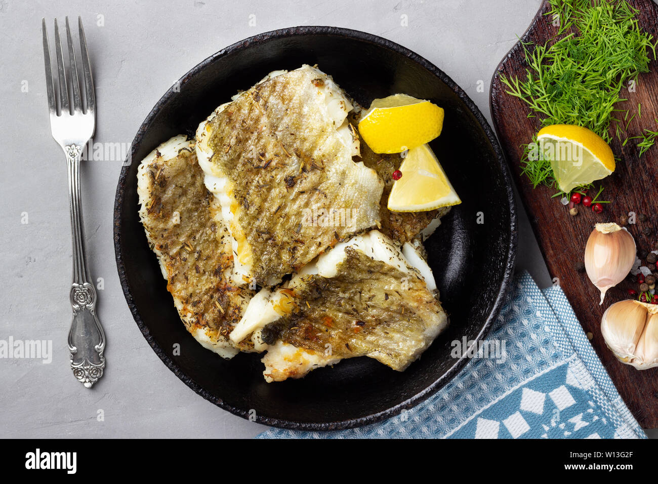 Fried cod fish fillet with spice in a cast iron pan. Top view Stock