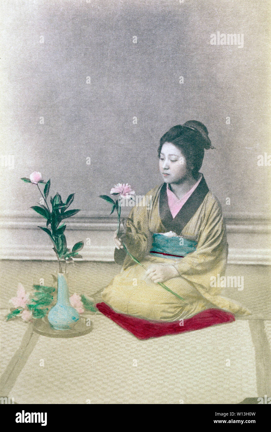 [ 1890s Japan - Ikebana Flower Arrangement ] —   Woman in kimono with traditional hairstyle doing 'ikebana', Japanese style flower arrangement.  During the Meiji and Taisho periods, ikebana and chado (tea ceremony) were a popular way to culturally enlighten oneself, especially for young women on the threshold of marriage.   19th century vintage albumen photograph. Stock Photo