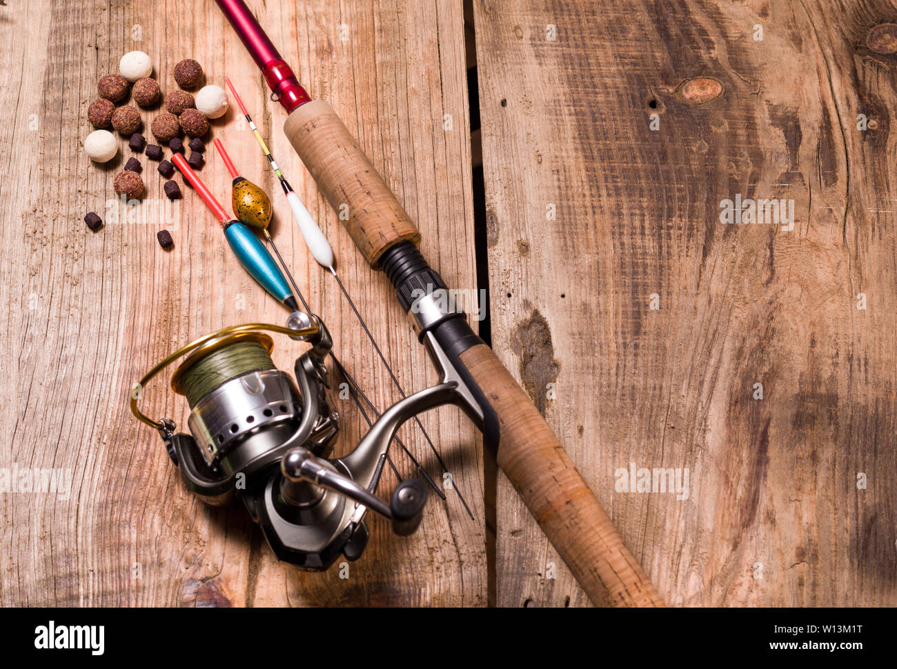 Fishing rod with reel and fishing line. Fishing floats and baits for carp.  Tackle on a wooden jetty Stock Photo - Alamy