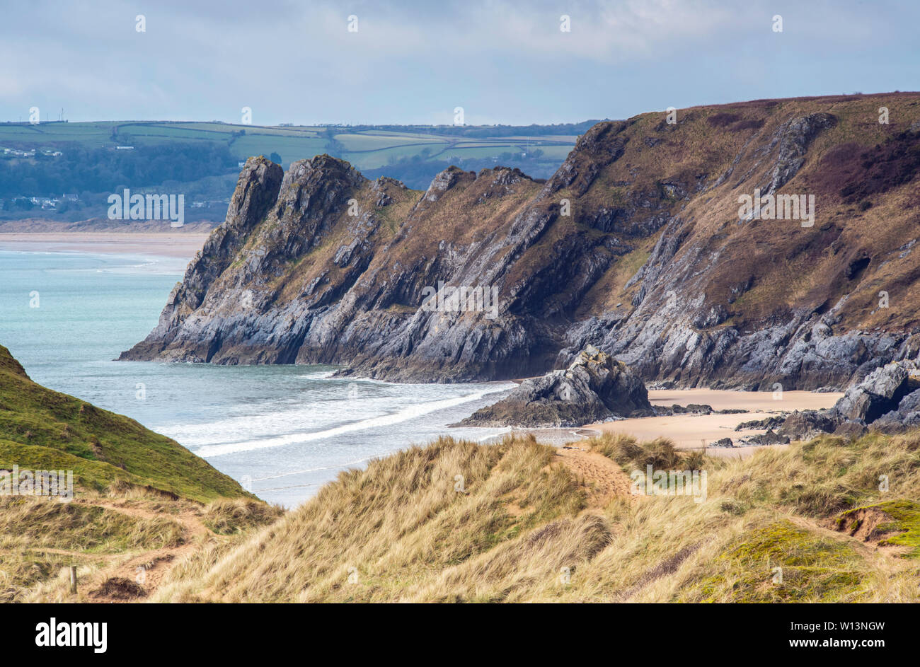 The cliffs of Great Tor and the beach of Three Cliffs Bay on the south Gower Coast on a cold and sunny day, South Wales Stock Photo