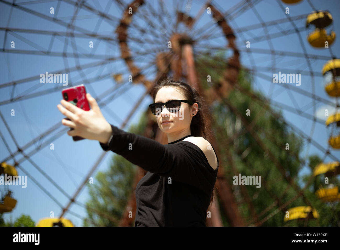 Girl taking selfie in Pripyat amusement park on the ferris wheel background Stock Photo
