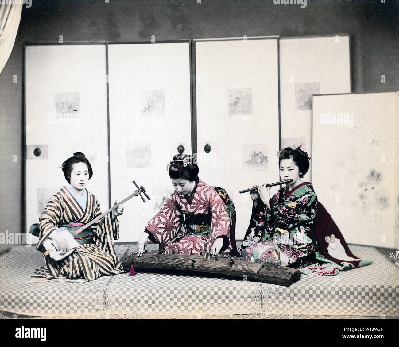 [ 1890s Japan - Geisha Playing Music ] —   Young Japanese women in kimono and traditional hairdo playing the shamisen (left), the koto (middle) and the fue (right).  19th century vintage albumen photograph. Stock Photo