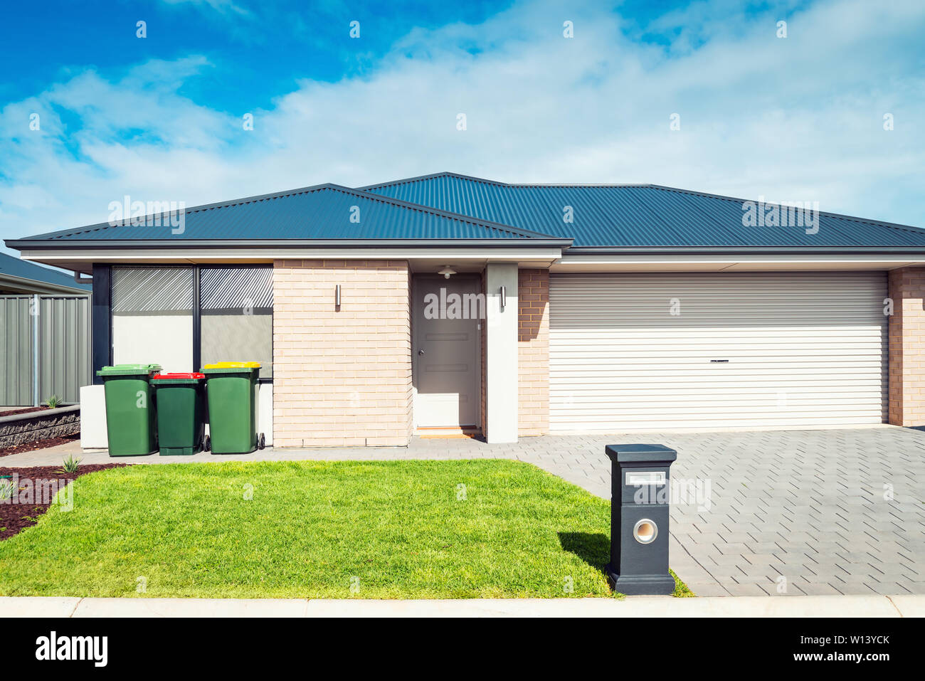 Brand new Australian house with double garage door, landscaping, waste bins and mailbox at front Stock Photo