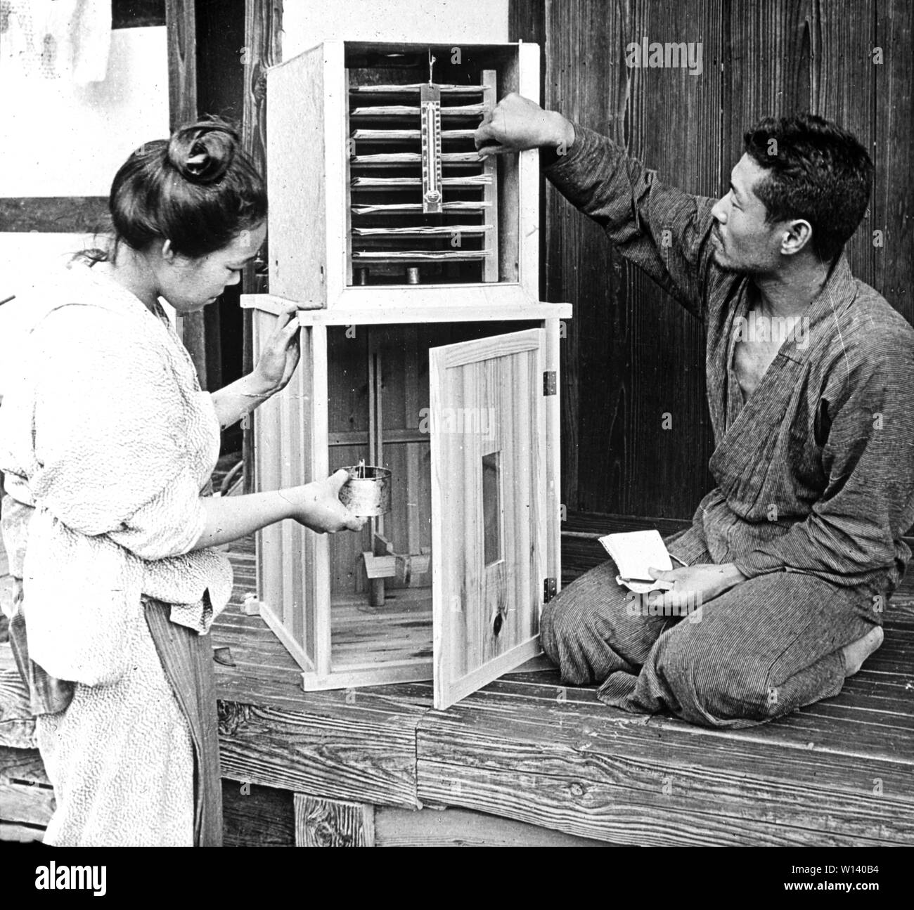 [ 1900s Japan - Silkworm Incubator ] —   A woman and a man work with a silkworm incubator.  20th century vintage glass slide. Stock Photo