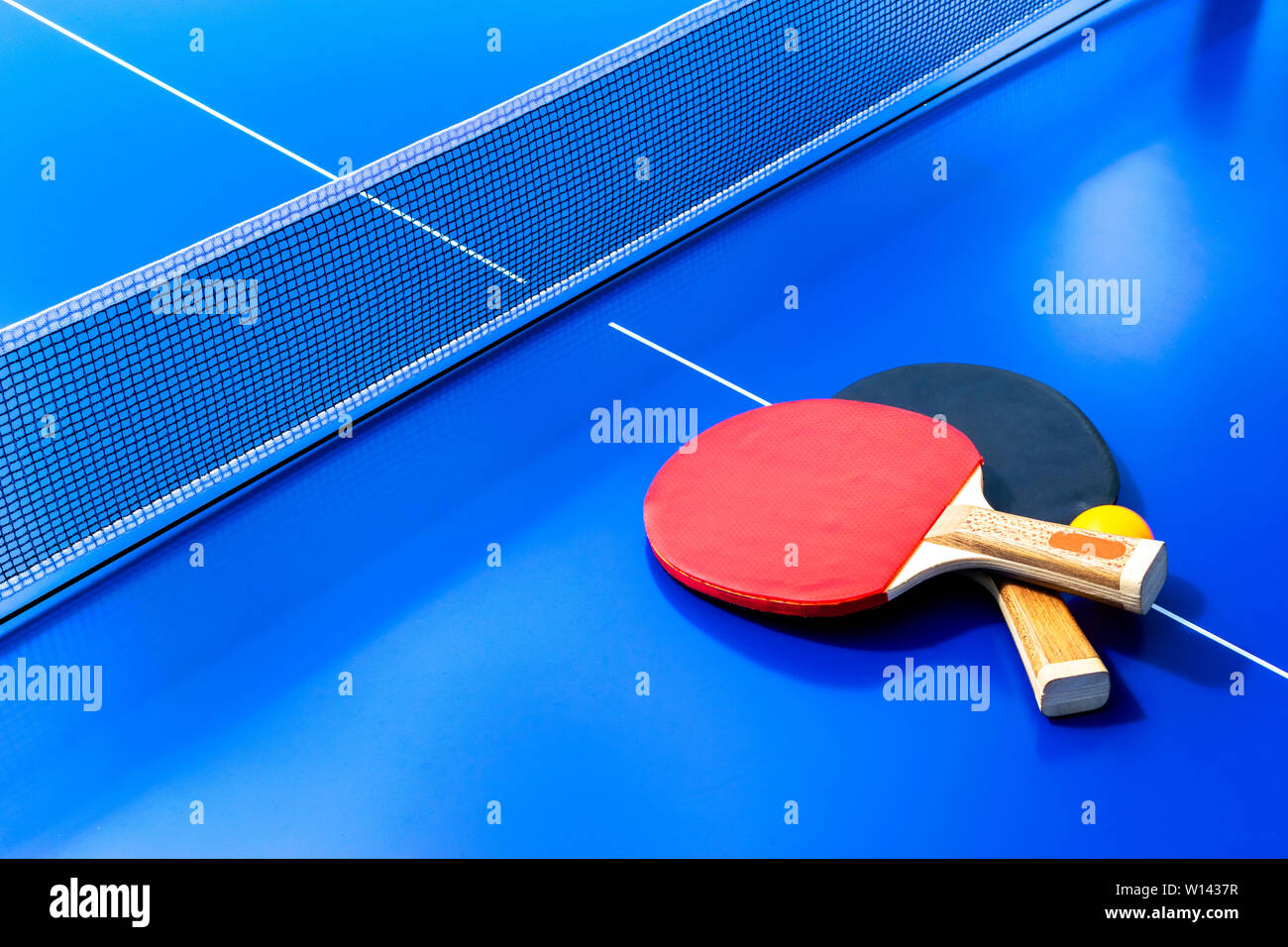 Blue table tennis or ping pong. Close-up ping-pong net. Close up ping pong net and line. Two table tennis or ping pong rackets or paddles  and ball on Stock Photo
