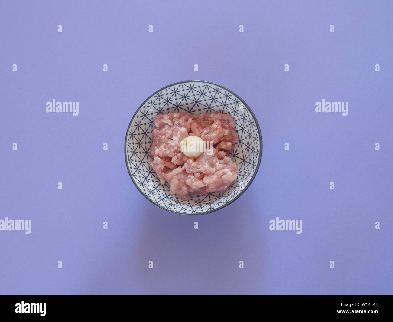 Minced pork meat in a bowl on purple background Stock Photo