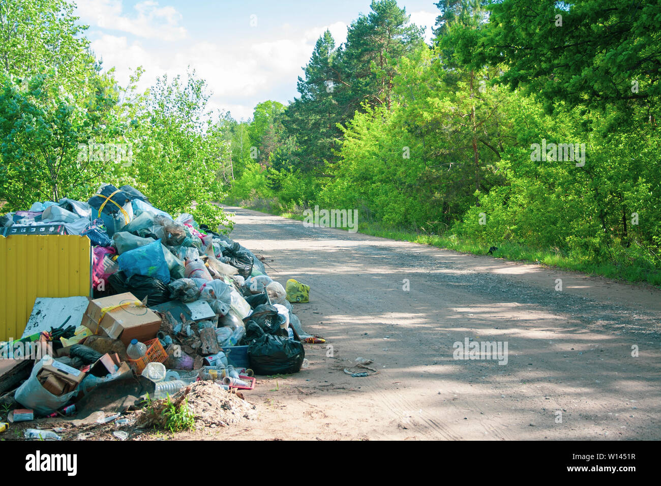 Illegal dump near the country sand road in the country on sunny day