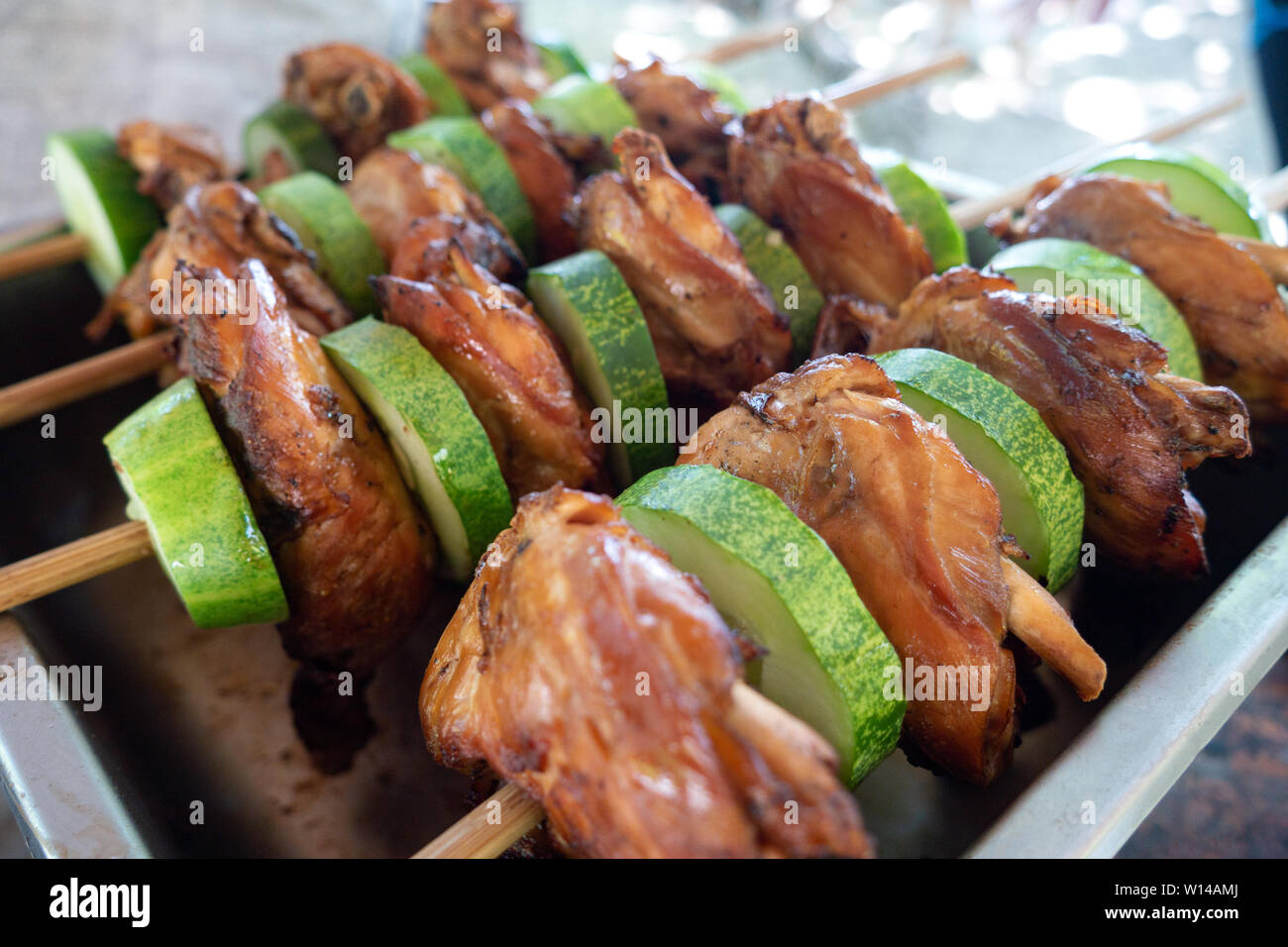 Filipino traditional authentic dish: philippine roasted chicken or pork barbecue on a stick with cucumber Stock Photo