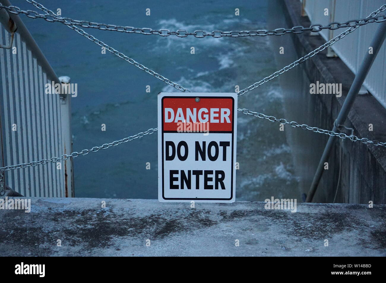 Danger - Do Not Enter sign warns beachgoers not to climb down stairs into rough waters on Lake Michigan's shore. Stock Photo