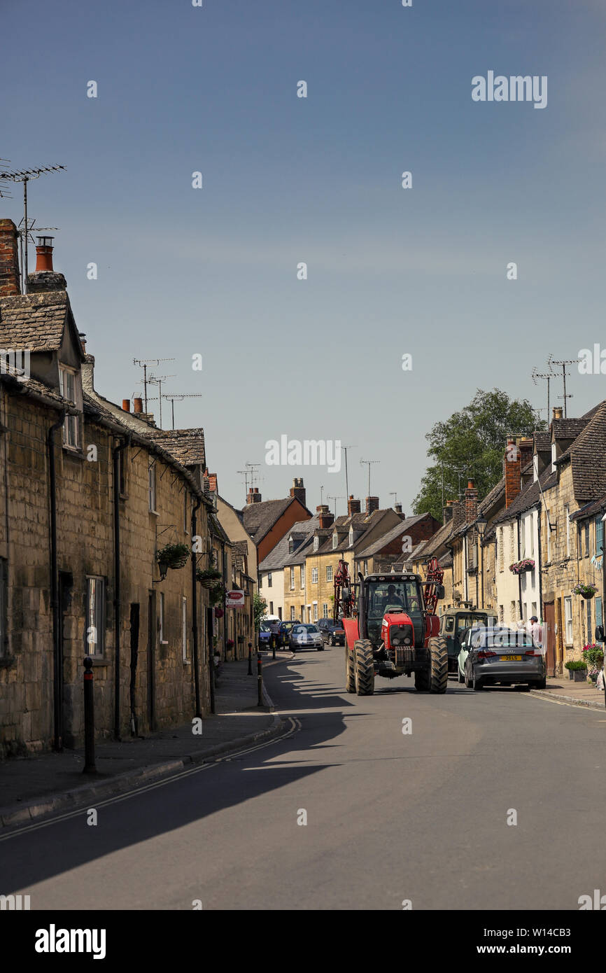 A farmer driving his tractor through the historic Cotswold town of Winchcombe, Gloucestershire UK Stock Photo