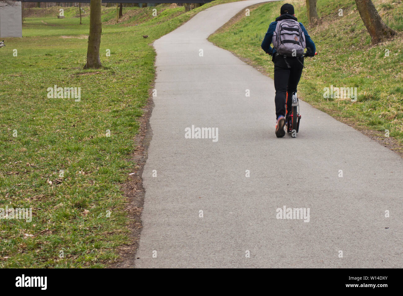 boy with backpack along a road in nature on a kick scooter Stock Photo