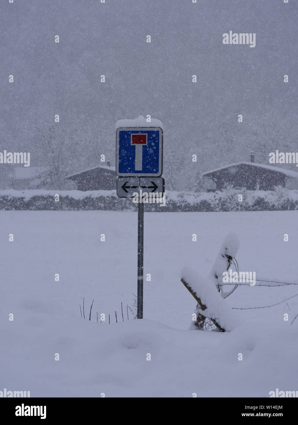 A dead end traffic sign on the edge of a snow-covered field in a heavy snow storm. Samoens, Haute Savoie, France. Stock Photo