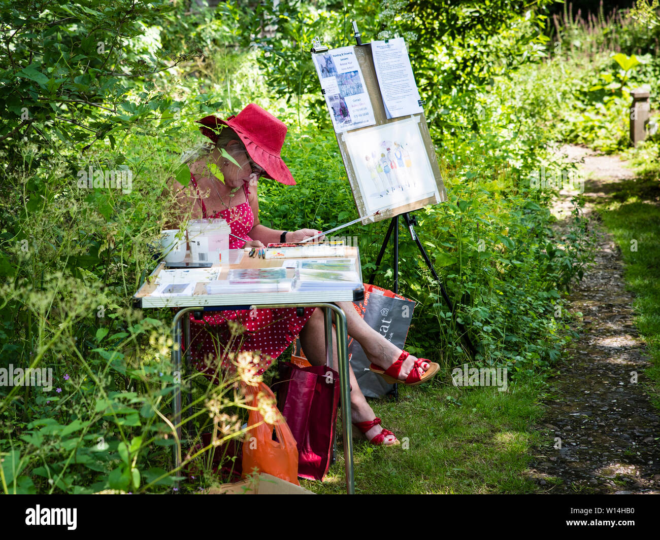 A lady artist in a red hat and dress painting in a sunny garden Stock ...