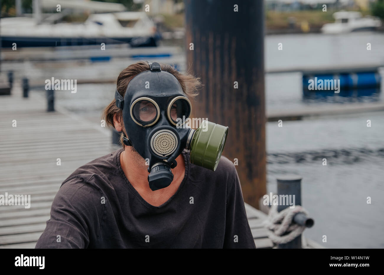 The man of the empty city looks into the distance wearing a gas mask in a city full of unclean air Stock Photo