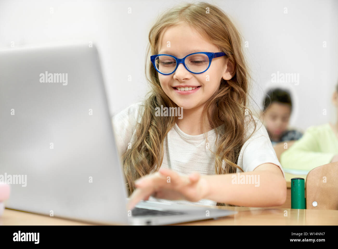 Beautiful smart girl sitting at desk at school and using modern ...
