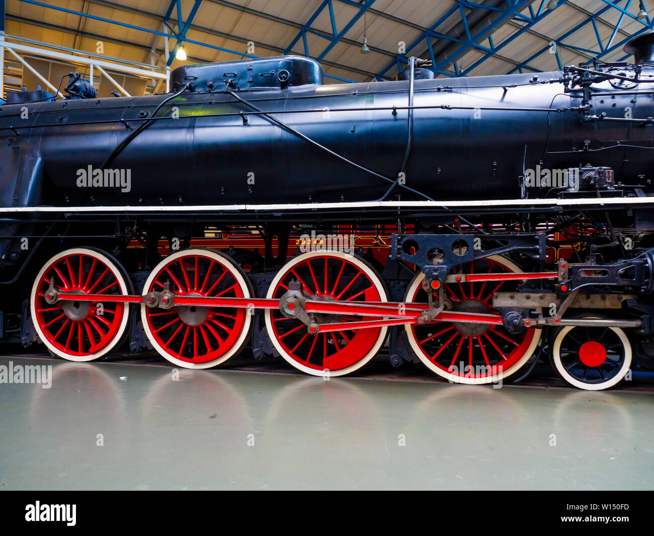 A 4-8-4 passenger steam locomotive from Chinese Railways built by Vulcan Foundry detail showing red driving wheels and valve gear Stock Photo