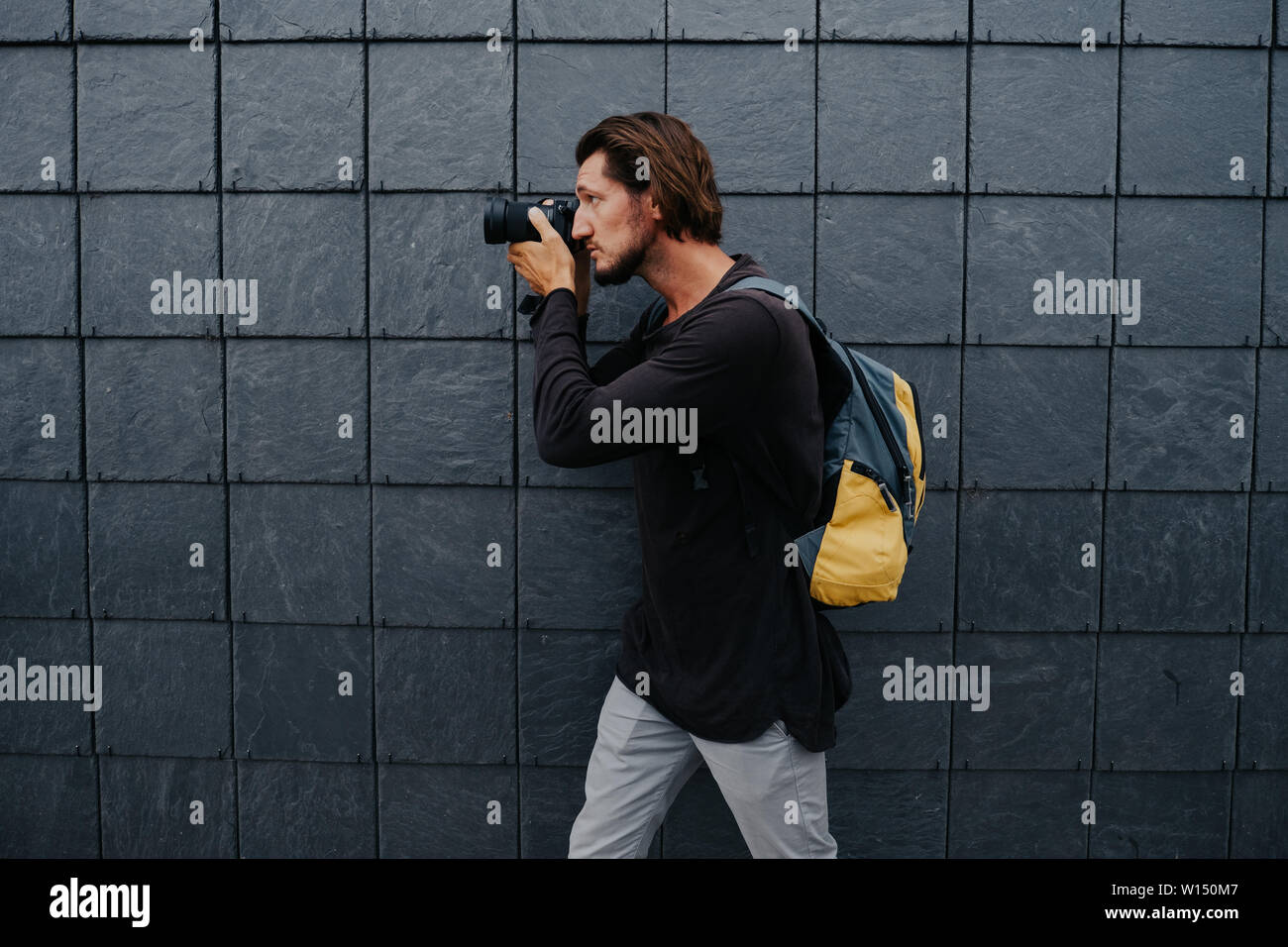 Stylish hipster photographer in a big city with a camera and a backpack on his back. Stock Photo