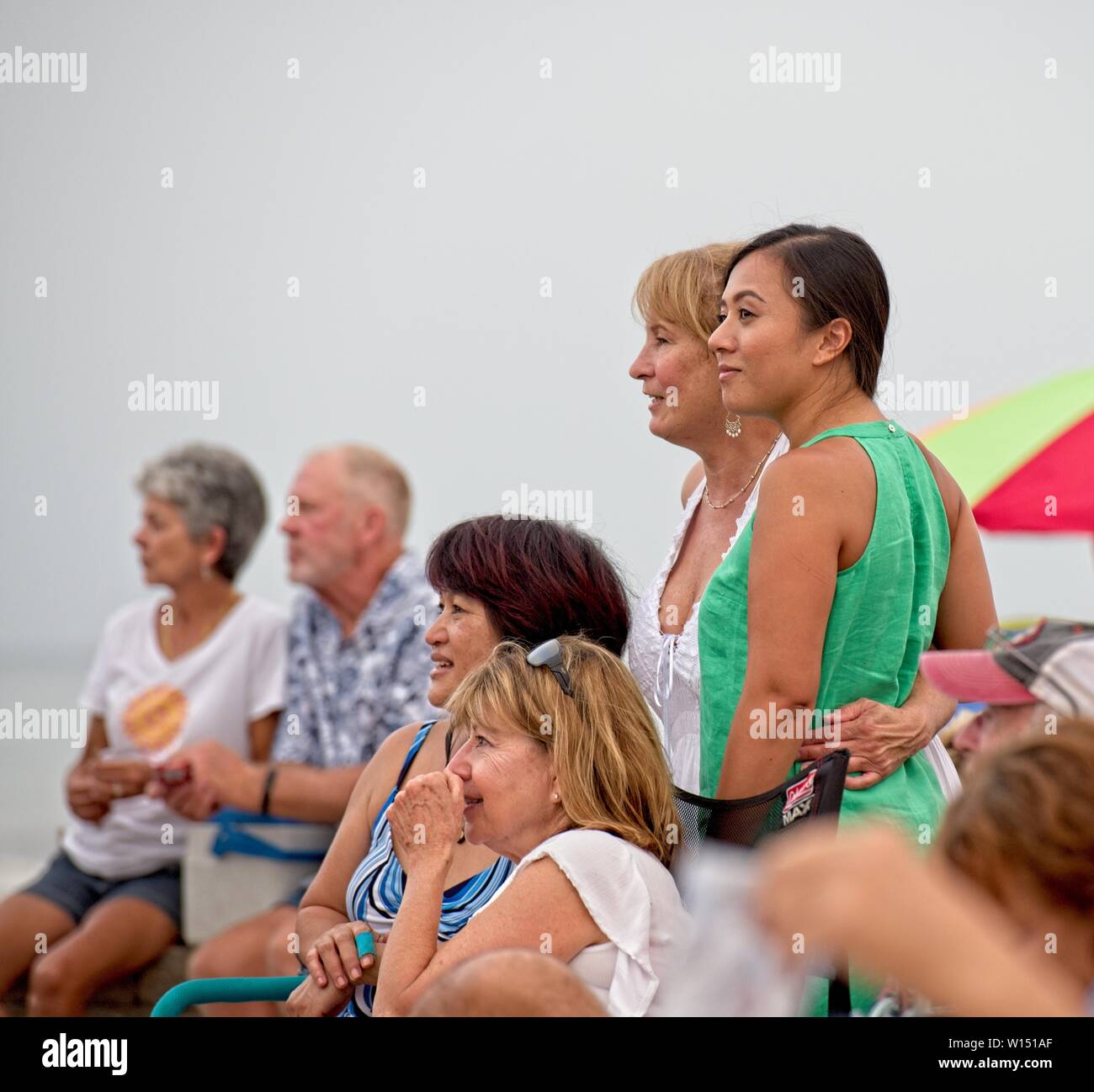 A small group of people watching a band perform at a Bands on the Beach Concert at Pensacola Beach, Florida USA Stock Photo