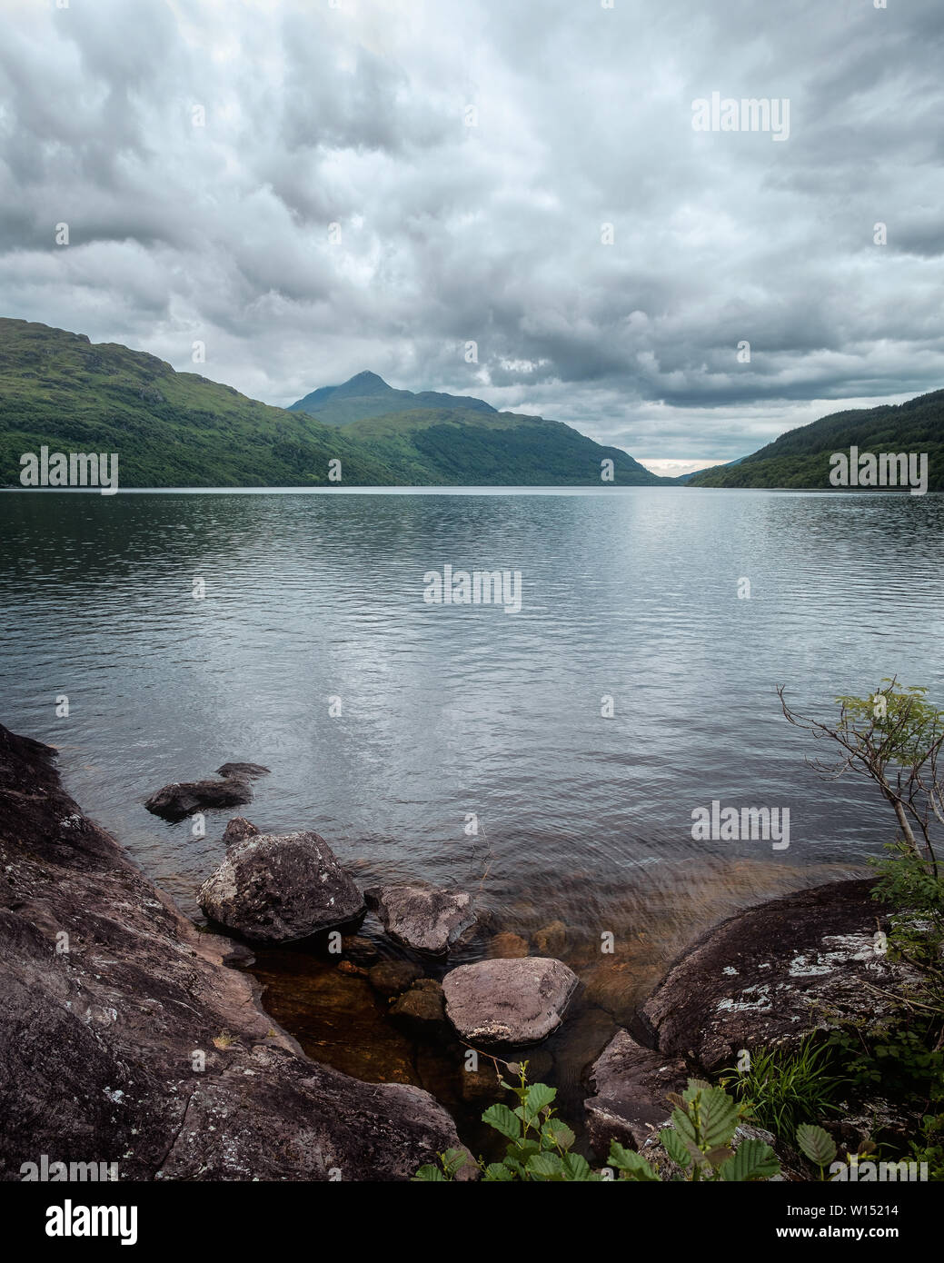 Scottish landscape on a lake with a stone shore and green mountains. Summer 2019. Loch Lomond, Scotland Stock Photo