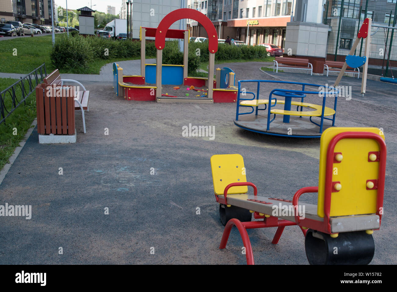 Children playground on yard activities in public park surrounded by green trees at sunlight morning. Children run, slide, swing,seesaw on modern playg Stock Photo