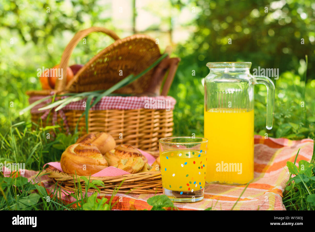 Picnic in nature. Picnic basket with fruit decanter juice and buns Stock Photo