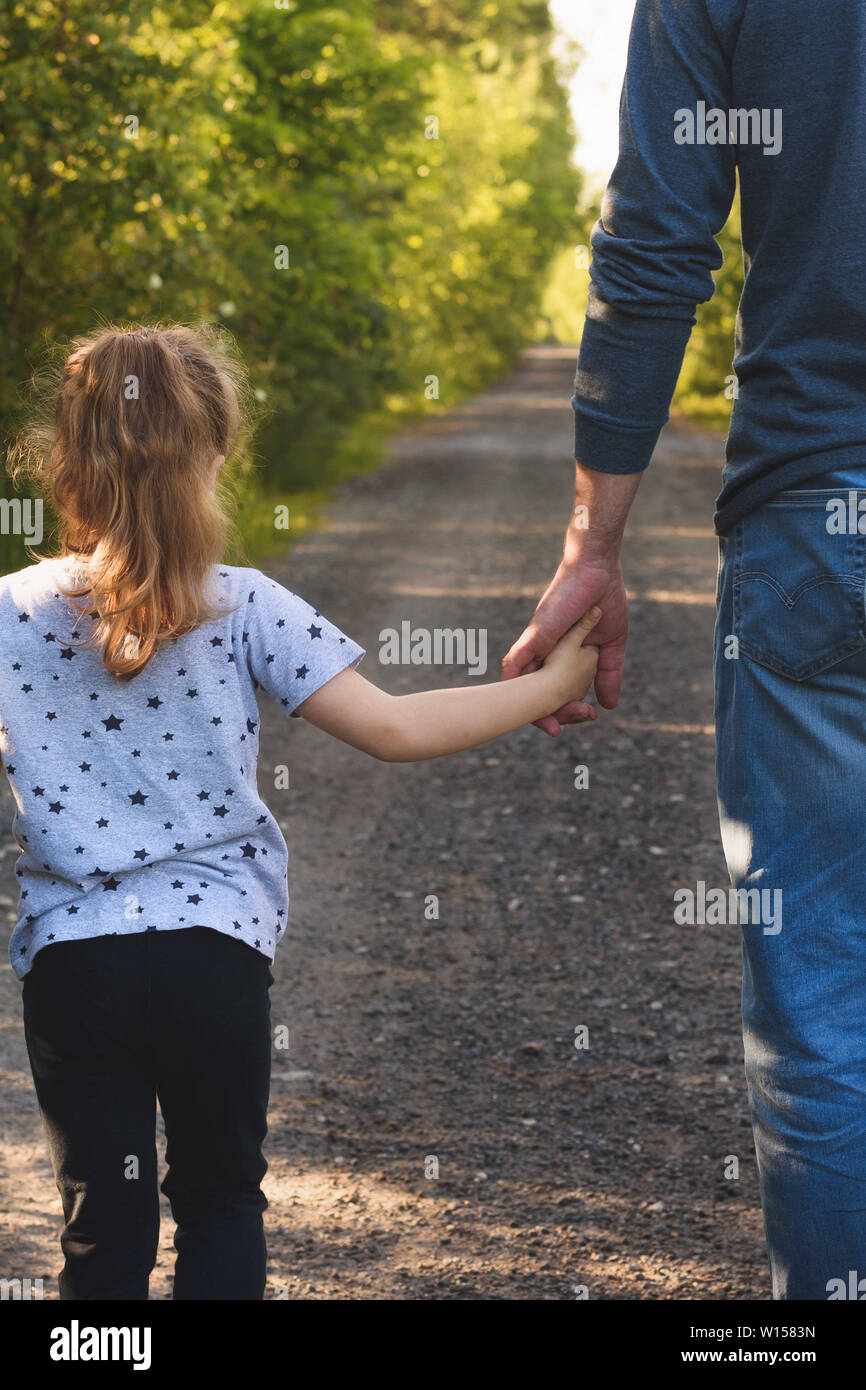Father and daughter walking in the park holding hands. We will love and  take care of you forever concept Stock Photo - Alamy