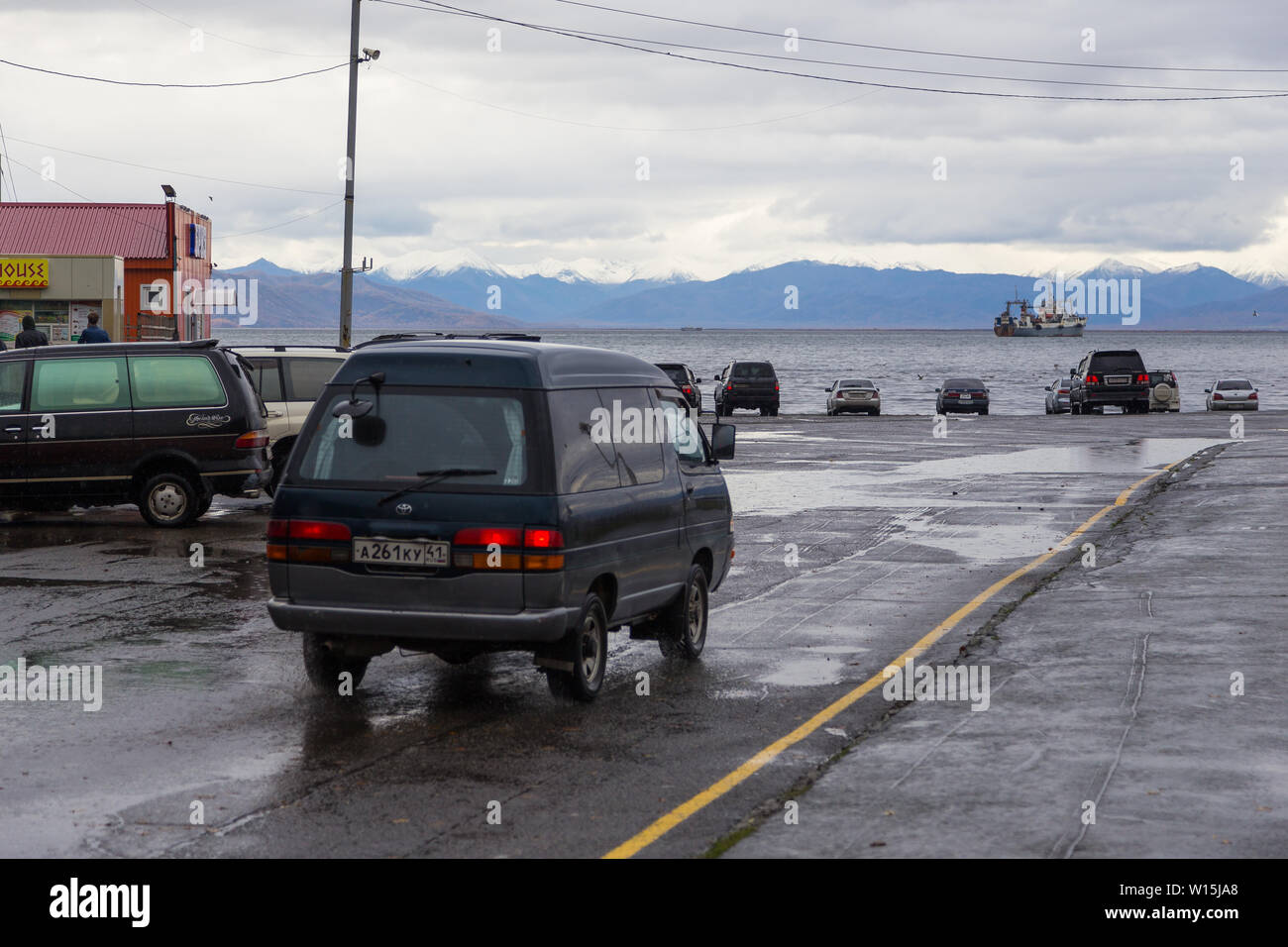 Petropavlovsk-Kamchatsky, Russia- 05 October 2014: Cars on the ca park near Avacha Bay. Ships standing in the roadstead, mountain in the background. Stock Photo