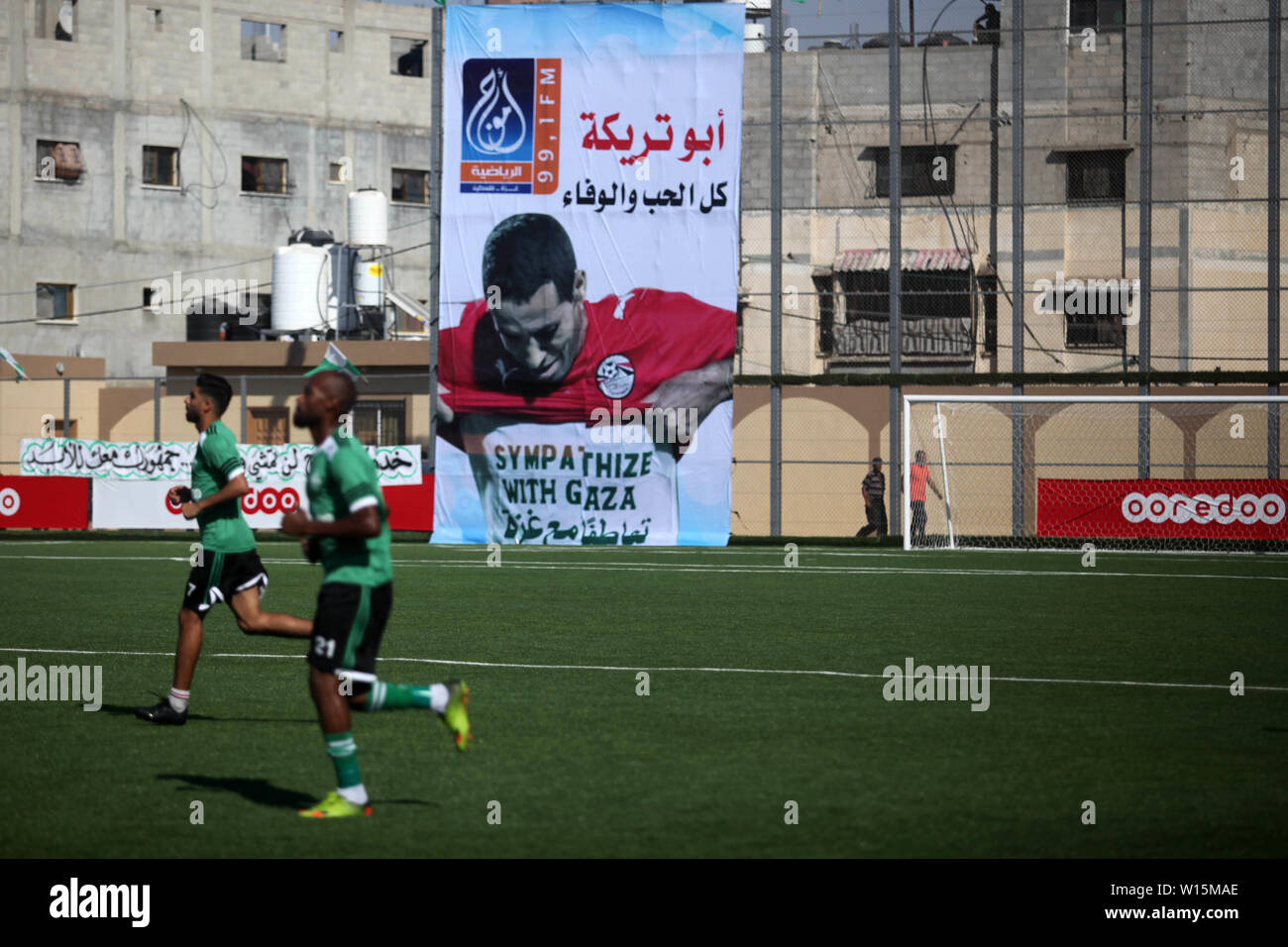 Rafah, Gaza Strip, Palestinian Territory. 30th June, 2019. A poster of Egyptian football player Mohammed Abu Trika is seen during a match between Palestinian players of Khadamat Rafah club (green T-shirt), and players of Balata youth club (yellow T-shirt), in the Palestine cup championship, in Rafah in the southern Gaza Strip on June 30. 2019. The game ended with a 1-1 draw in the first leg of the Palestine Cup final Credit: Mahmoud Ajjour/APA Images/ZUMA Wire/Alamy Live News Stock Photo