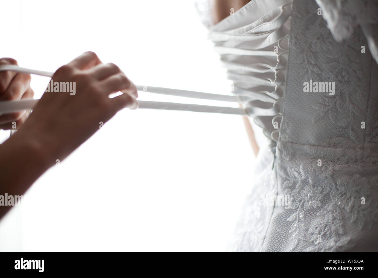 Bride from the back. Lacing the wedding dress Stock Photo - Alamy